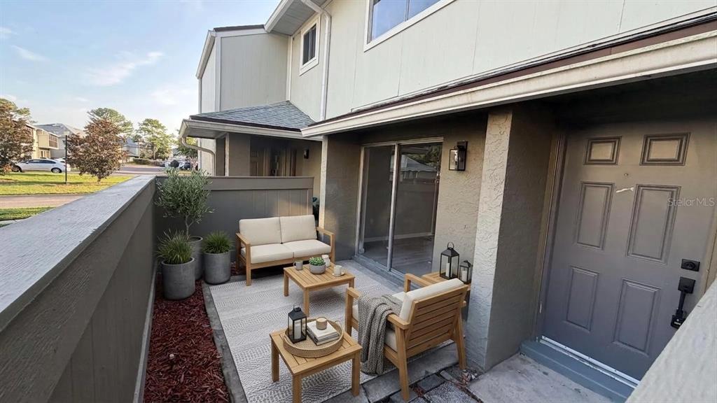 A small patio features outdoor furniture, a rug, and potted plants next to a front door — 4578 PHEASANT RUN DRIVE UNIT 7B, ORLANDO, FL