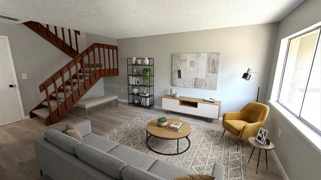 A living room features a wooden staircase, gray sofa, yellow armchair, and a round coffee table — 4578 PHEASANT RUN DRIVE UNIT 7B, ORLANDO, FL