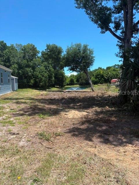 A cleared residential lot features a small pond with a fountain in the background — 1371 VINE STREET, DAYTONA BEACH, FL
