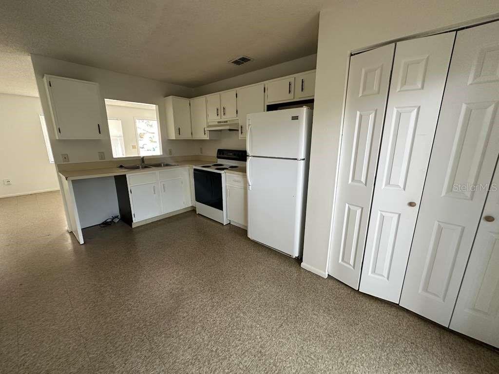 A kitchen features white cabinets, a white refrigerator, a stove, and light-colored vinyl flooring — 430 S HILL AVENUE UNIT 432, DELAND, FL