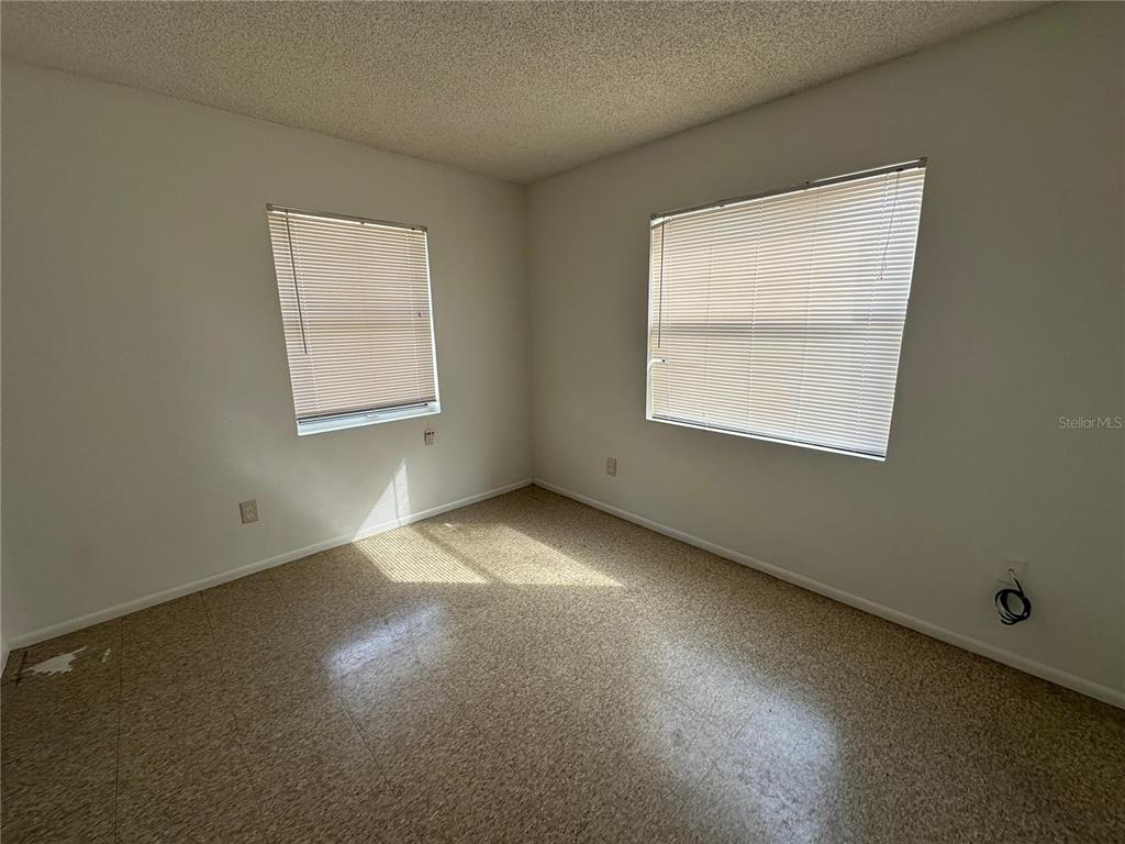An empty bedroom features white walls, two windows with blinds, and speckled vinyl flooring — 430 S HILL AVENUE UNIT 432, DELAND, FL