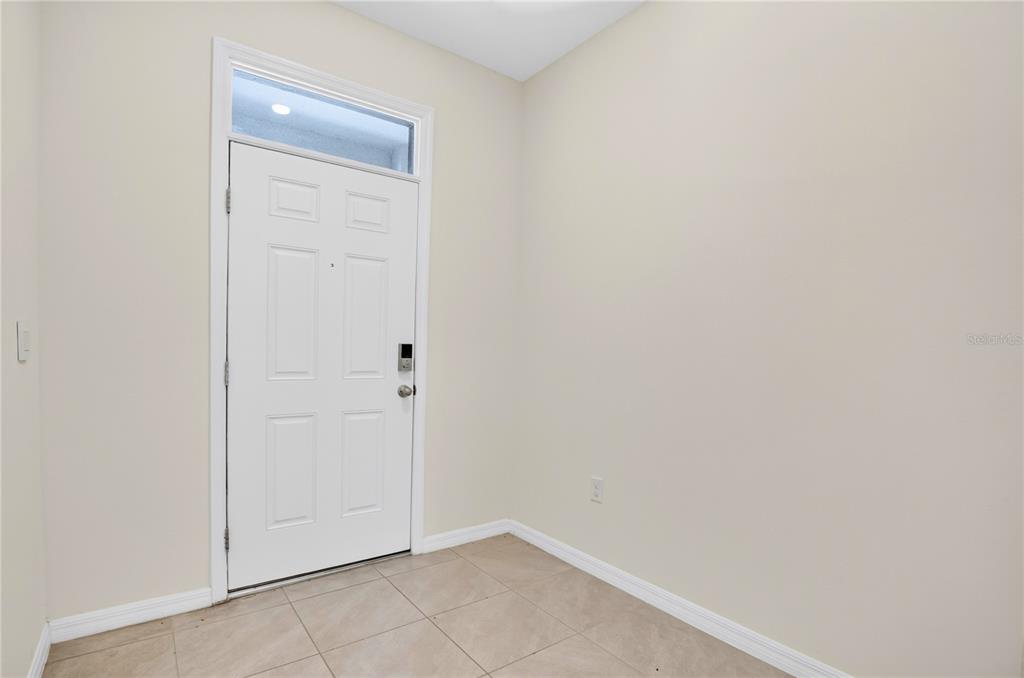 An entryway with light-colored walls, tiled flooring, and a white front door with a transom — 33028 TULIP PETAL LANE, WESLEY CHAPEL, FL