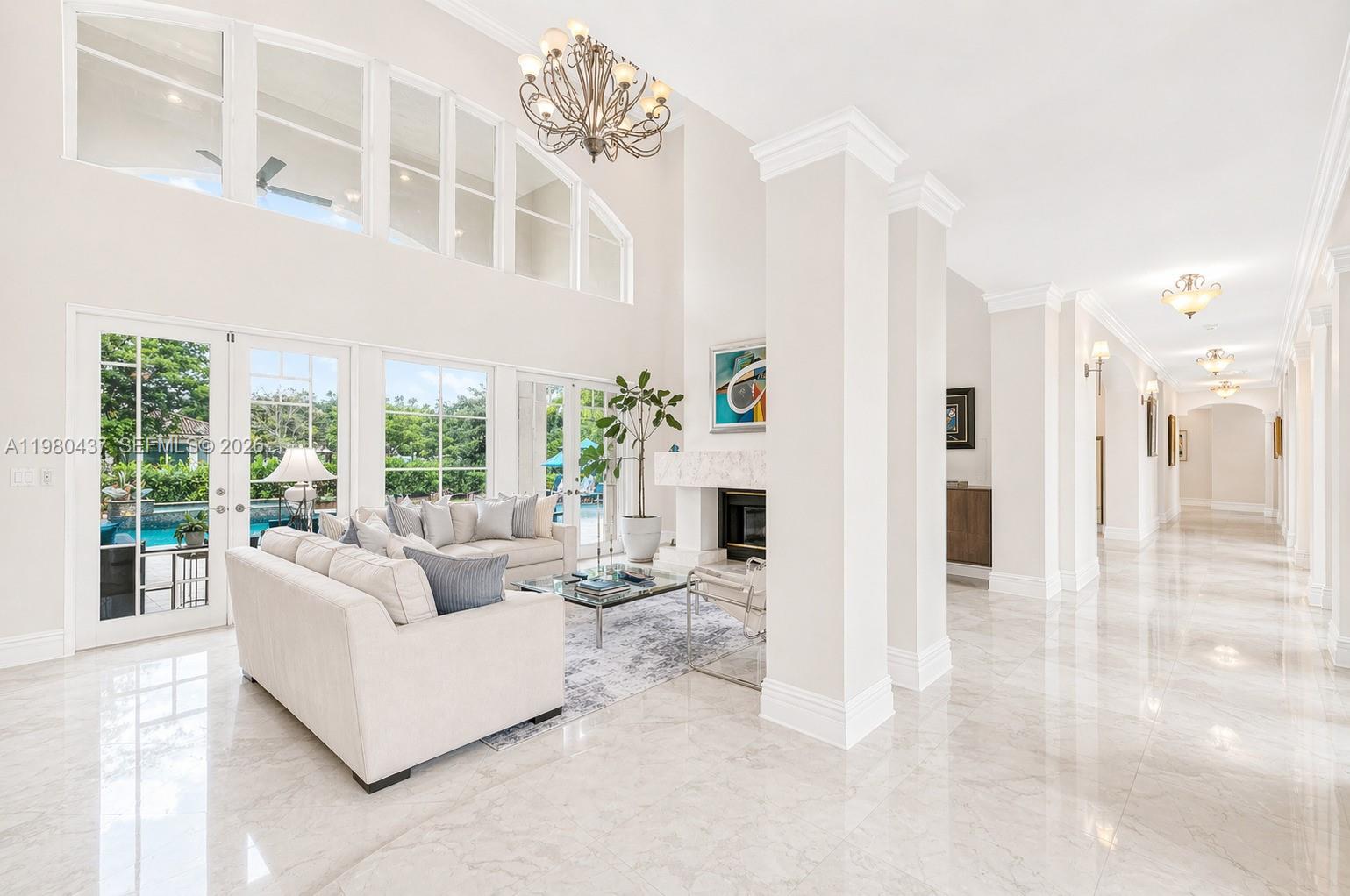A spacious living room features high ceilings, marble floors, a fireplace, and large glass doors — 13425 SW 37th Pl, Davie FL 33330, DAVIE, FL