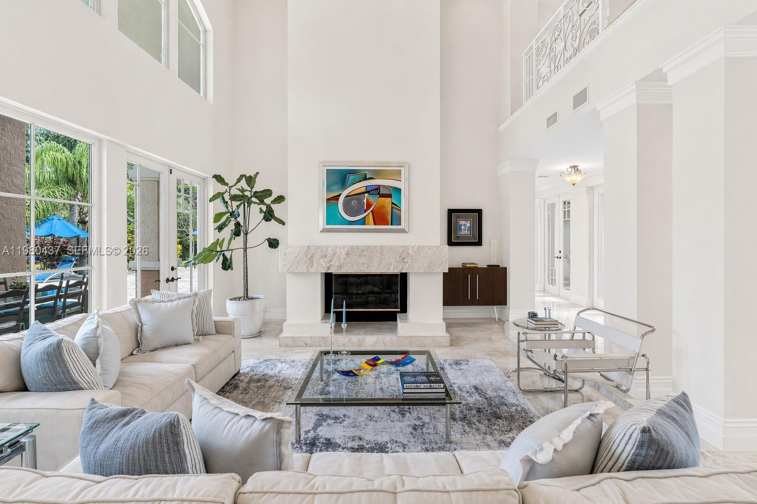A bright, high-ceilinged living room features a marble fireplace, white sofas, and glass tables — 13425 SW 37th Pl, Davie FL 33330, DAVIE, FL