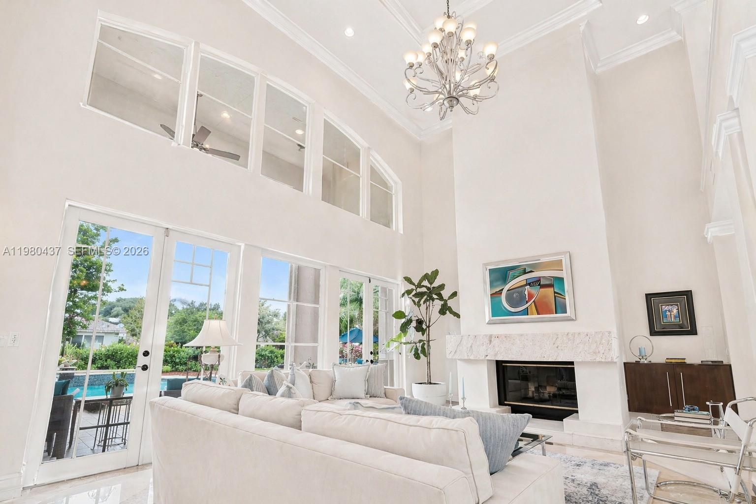 A bright living room features a double-height ceiling, a fireplace, and large glass doors — 13425 SW 37th Pl, Davie FL 33330, DAVIE, FL