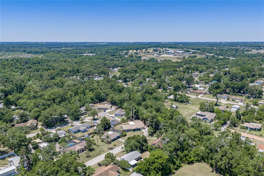 An aerial view shows a single-story house with a grey roof surrounded by dense trees — 37634 HIDDEN PARK COURT, DADE CITY, FL