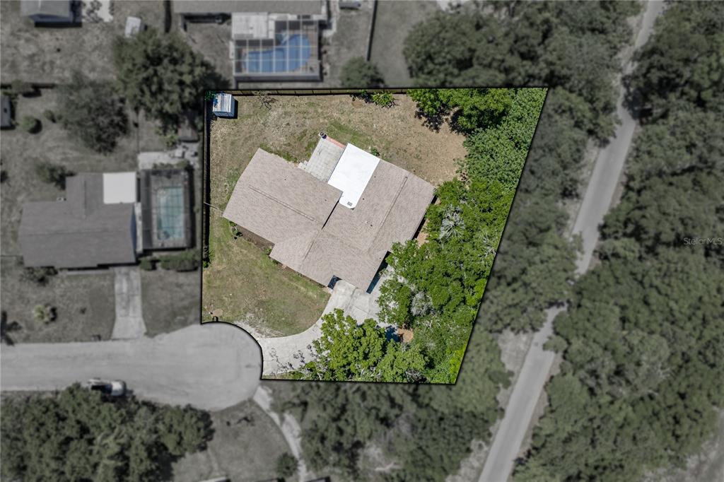 This aerial view shows a residential property with a house, driveway, and surrounding yard — 37634 HIDDEN PARK COURT, DADE CITY, FL