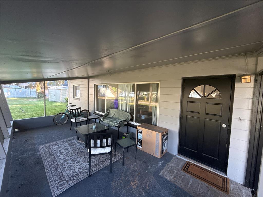 A covered patio features a black door, outdoor furniture, and a patterned area rug — 903 N HARBOR TERRACE, TAVARES, FL