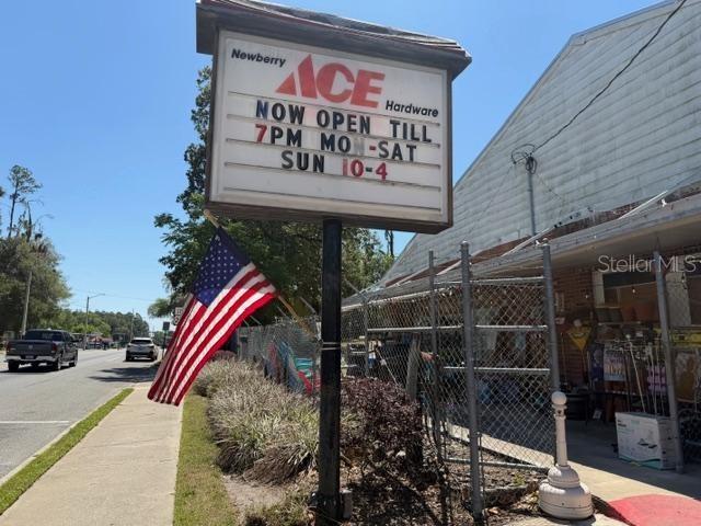An Ace Hardware sign stands next to an American flag and a building exterior — 25155 W NEWBERRY ROAD, NEWBERRY, FL