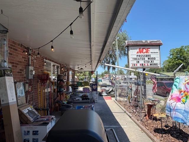 An outdoor walkway at an Ace Hardware store features string lights and merchandise displays — 25155 W NEWBERRY ROAD, NEWBERRY, FL