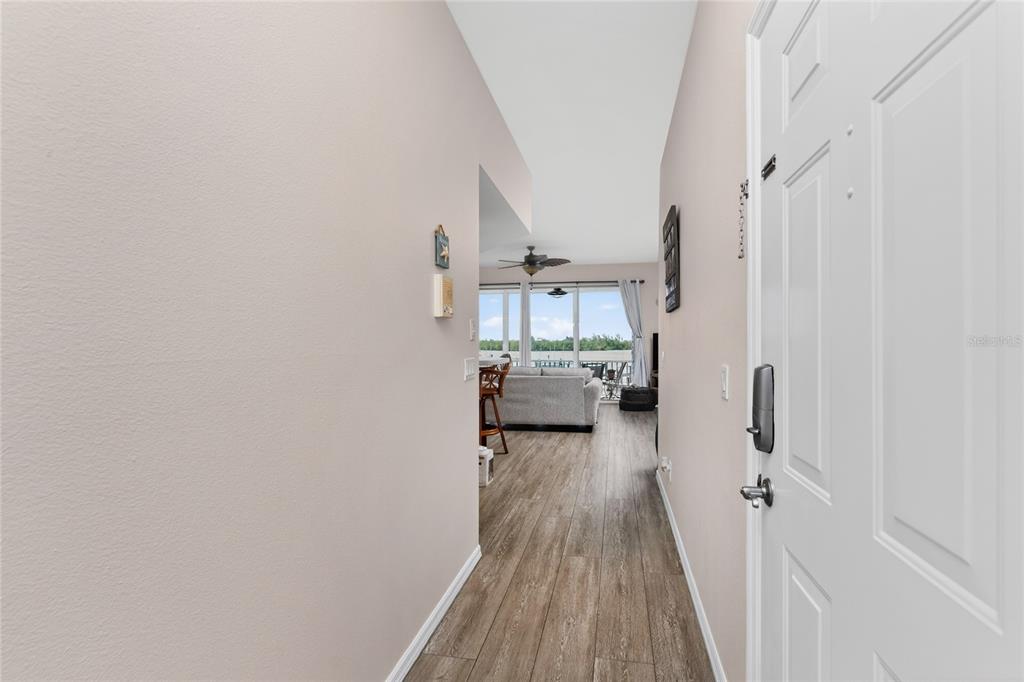 A view from an entryway looking down a hallway toward a living room with balcony — 1390 BEACH ROAD UNIT 1, ENGLEWOOD, FL