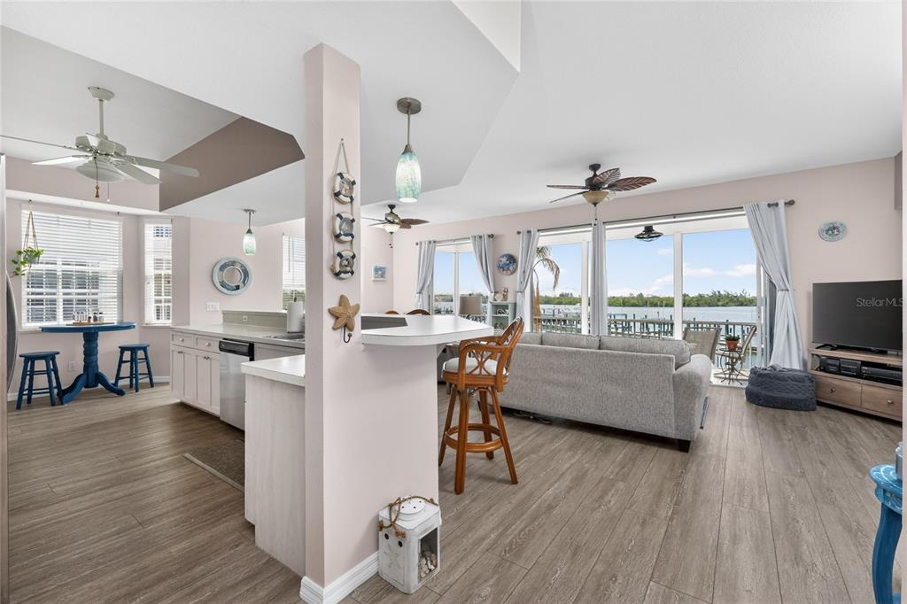 An open-concept living area with a kitchen, breakfast bar, and sliding doors overlooking the water — 1390 BEACH ROAD UNIT 1, ENGLEWOOD, FL