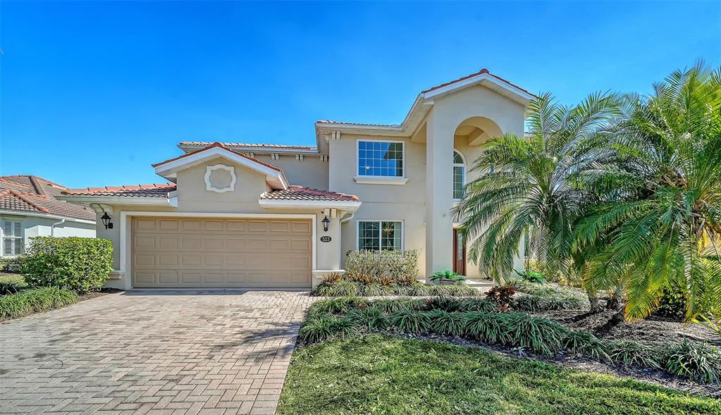 A two-story house with a beige stucco exterior, a tile roof, and a paved driveway — 523 GRAND PRESERVE COVE, BRADENTON, FL
