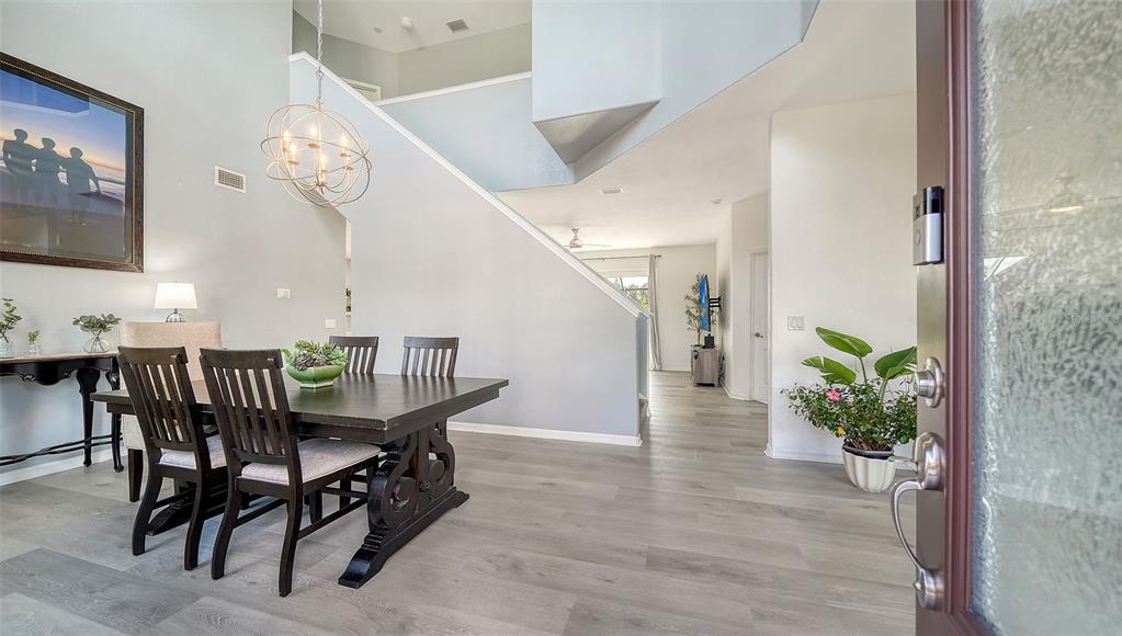 A dining area with a dark wood table and chairs sits near a staircase entrance — 523 GRAND PRESERVE COVE, BRADENTON, FL