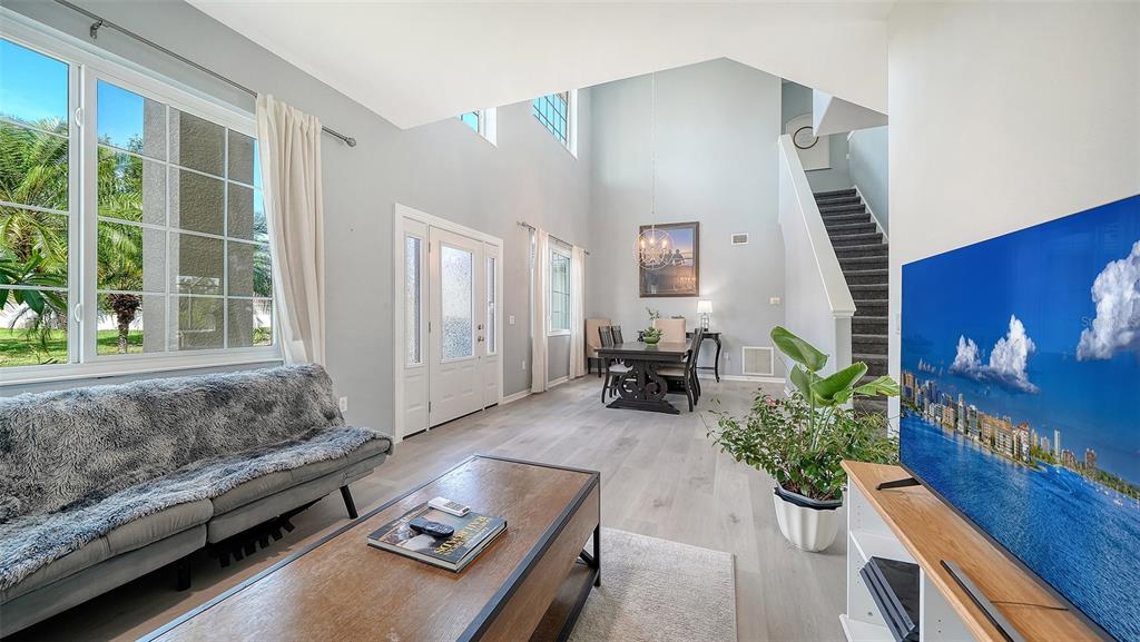 A living and dining area with high ceilings, light wood floors, and a staircase — 523 GRAND PRESERVE COVE, BRADENTON, FL