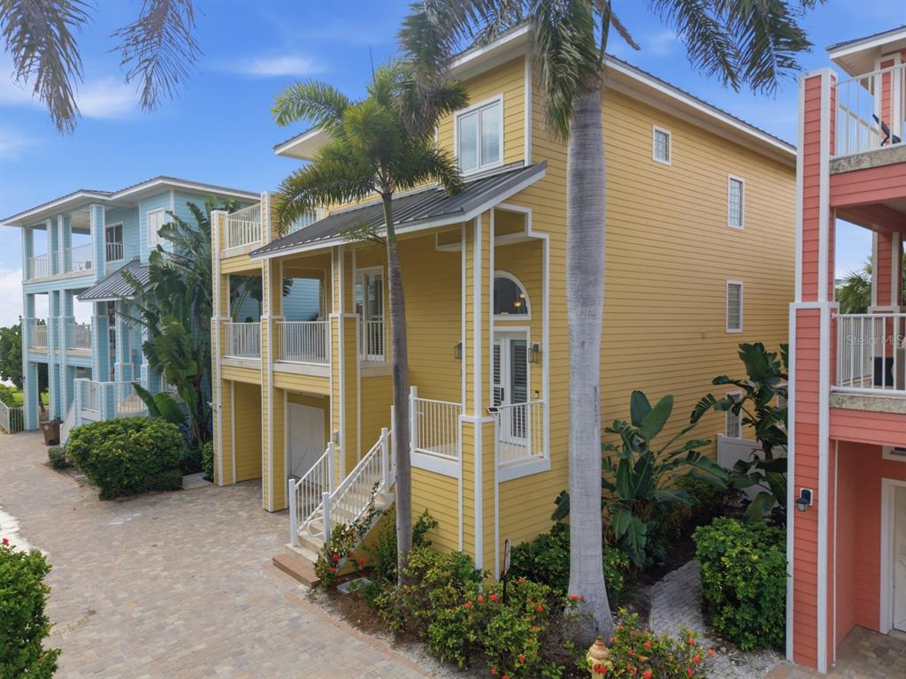 A three-story yellow house with a metal roof, balconies, and a paved driveway — 2718 GULF BOULEVARD UNIT 2, INDIAN ROCKS BEACH, FL