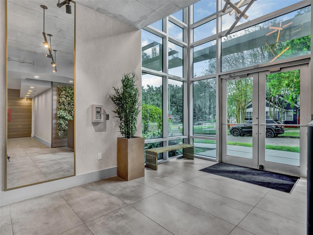 A modern building lobby features large windows, a tall mirror, tile flooring, and glass doors — 525 E JACKSON STREET UNIT 508, ORLANDO, FL