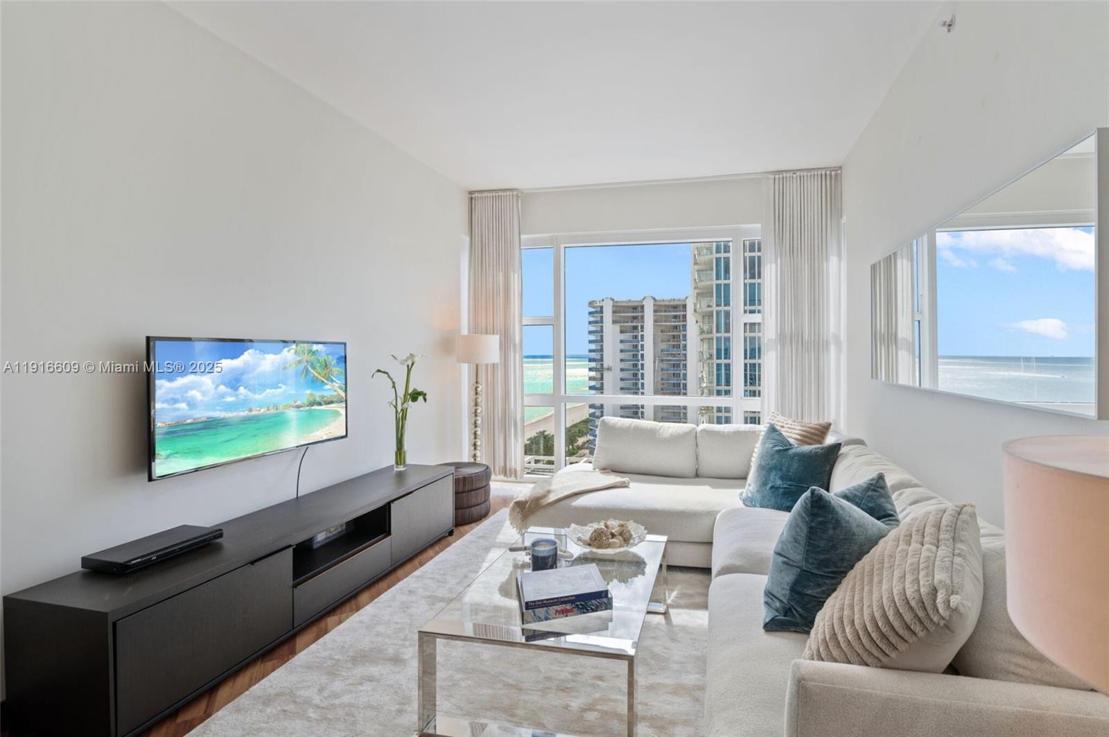 A living room features a white sectional sofa, glass coffee table, and ocean view windows — 6801 Collins Ave, Miami Beach FL 33141, MIAMI BEACH, FL