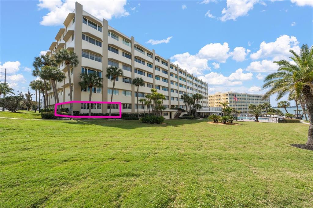 A multi-story apartment building with a pink rectangle highlighting the ground-floor windows — 100 BLUFF VIEW DRIVE UNIT 114A, BELLEAIR BLUFFS, FL