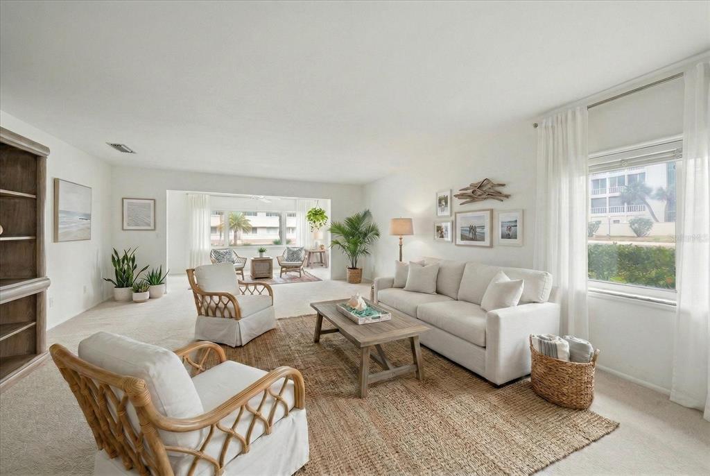 A bright living room features a beige sofa, rattan armchairs, and a natural fiber rug — 100 BLUFF VIEW DRIVE UNIT 114A, BELLEAIR BLUFFS, FL