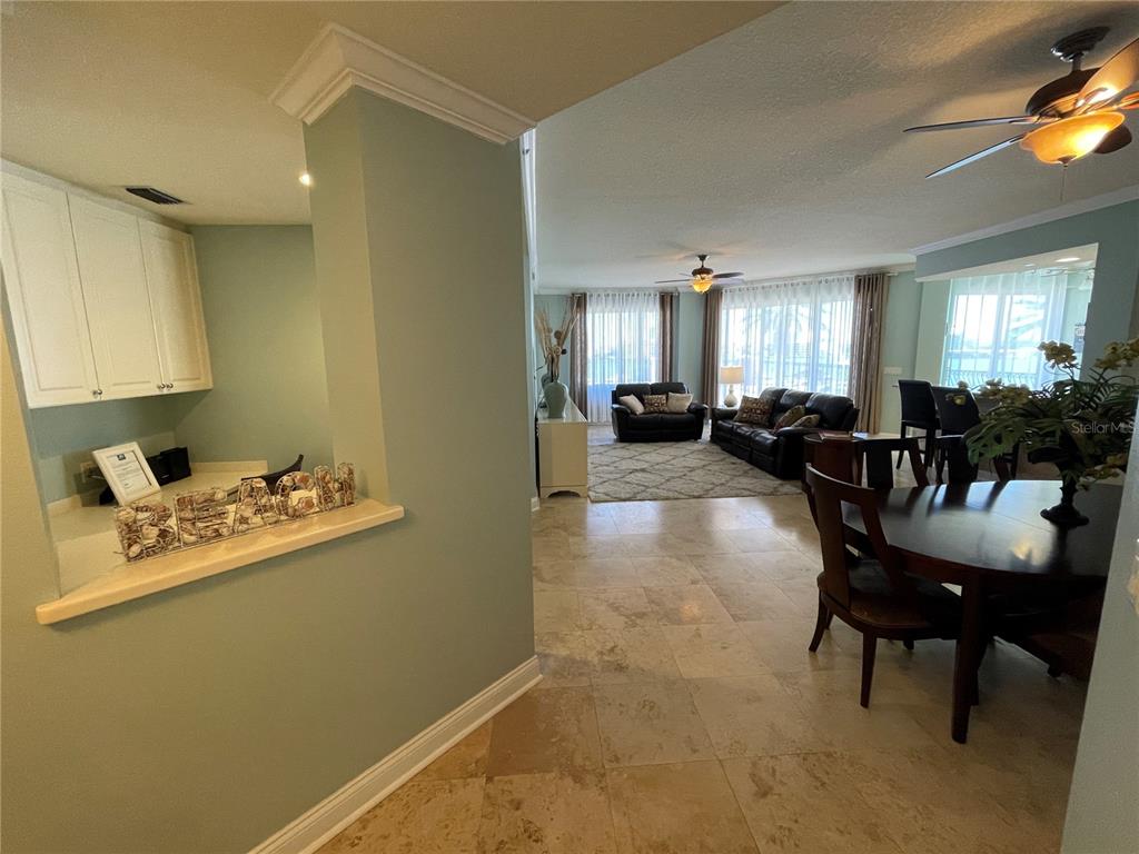 An open-concept living and dining area features tile flooring, light green walls, and ceiling fans — 521 MANDALAY AVENUE UNIT 309, CLEARWATER BEACH, FL