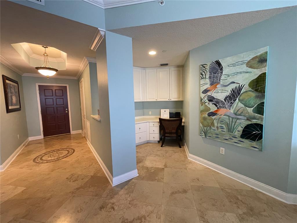 An entryway features stone tile flooring, a built-in desk, and a large bird painting — 521 MANDALAY AVENUE UNIT 309, CLEARWATER BEACH, FL