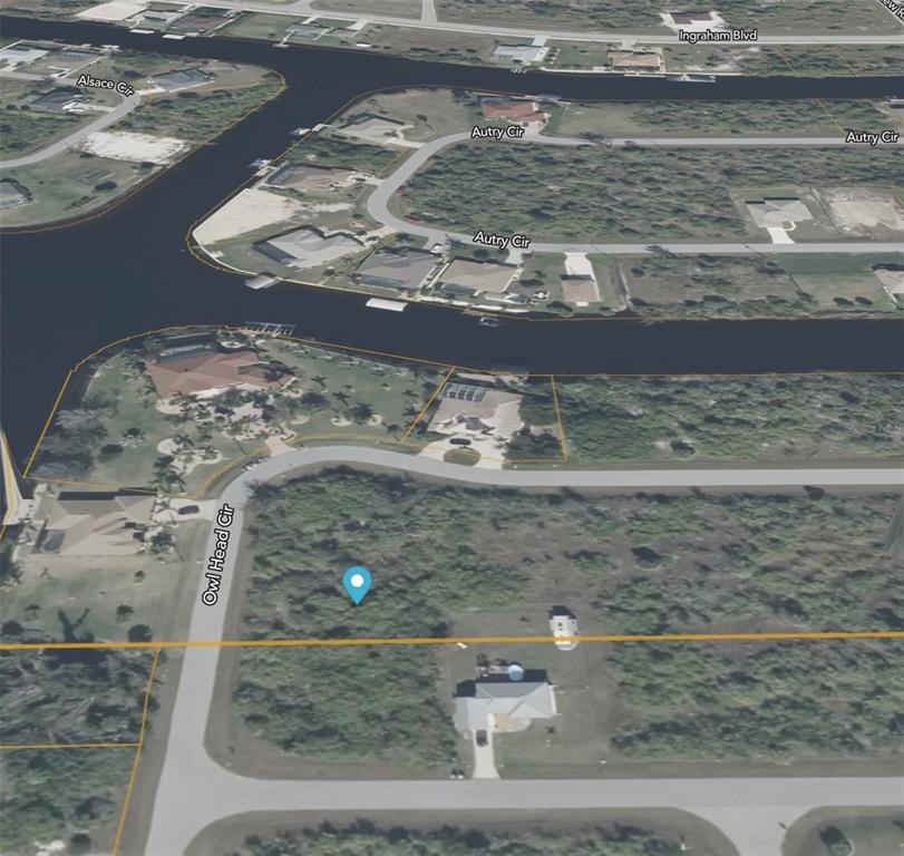 An aerial view shows a vacant residential lot marked with a blue pin near water — 10185 OWL HEAD CIRCLE, PORT CHARLOTTE, FL
