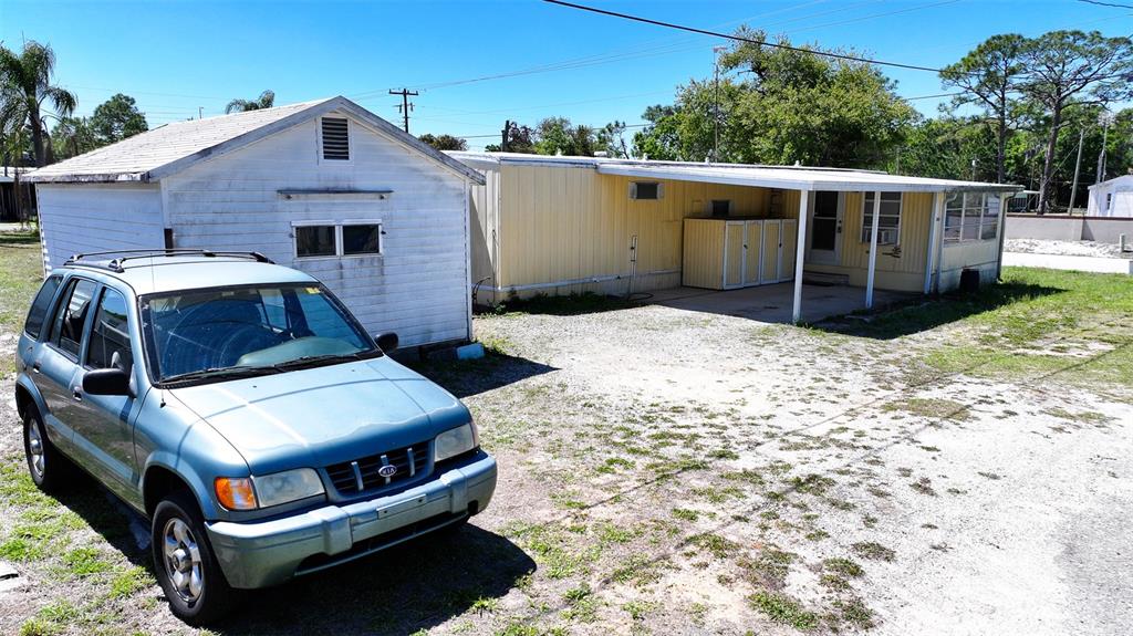A light blue SUV is parked in front of a white shed and yellow mobile home — 2400 SAN MIGUEL AVENUE, AVON PARK, FL