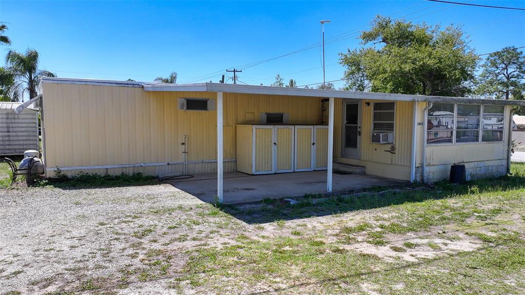 A single-story mobile home features a covered carport area and light yellow metal siding — 2400 SAN MIGUEL AVENUE, AVON PARK, FL
