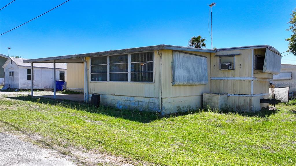 A single-story mobile home with a metal carport and an attached shed on a lot — 2400 SAN MIGUEL AVENUE, AVON PARK, FL