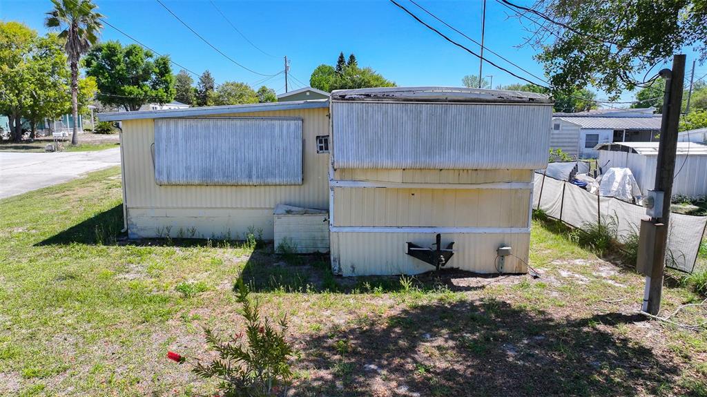 The exterior of a weathered, light-colored mobile home sits on a grassy lot — 2400 SAN MIGUEL AVENUE, AVON PARK, FL