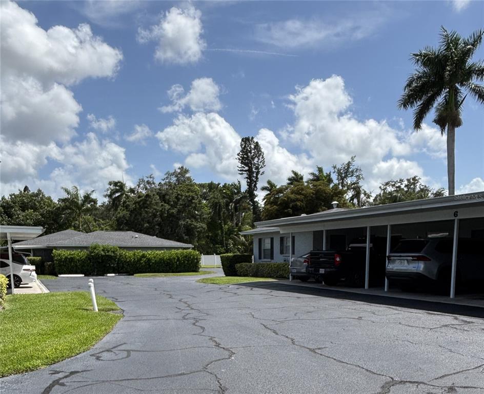An exterior view shows a paved parking area with covered carports and surrounding landscaping — 2115 9TH AVENUE W UNIT 6B, BRADENTON, FL