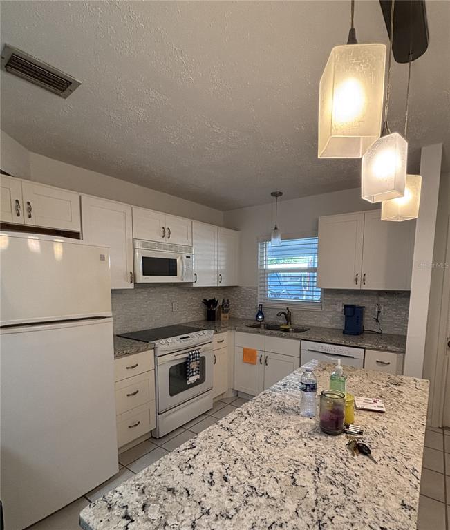 A kitchen features white cabinets, granite countertops, a kitchen island, and stainless steel appliances — 2115 9TH AVENUE W UNIT 6B, BRADENTON, FL