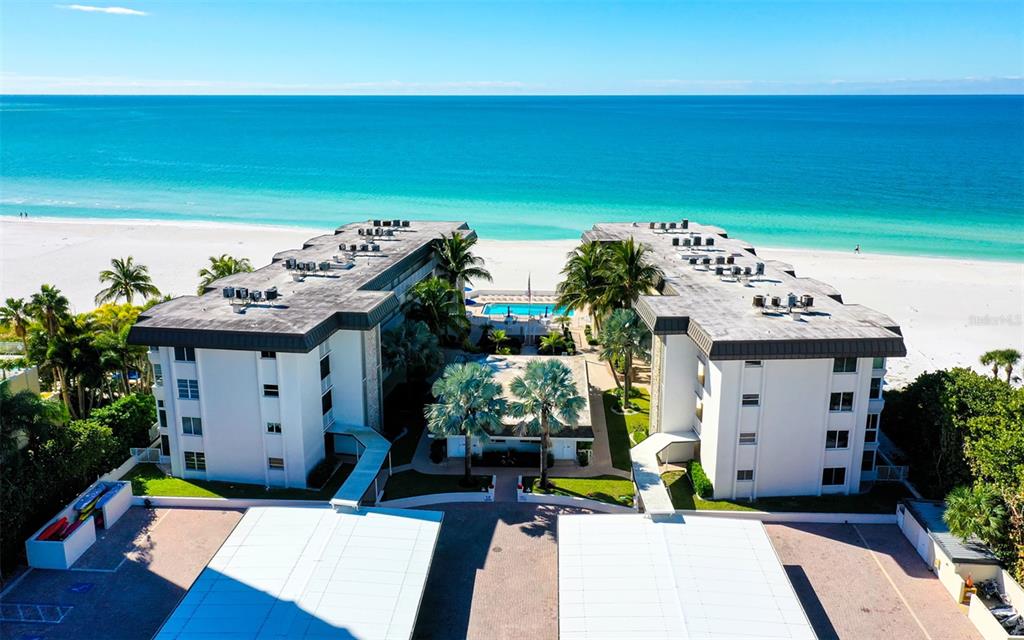 An aerial view shows a multi-story apartment building, low-rise residential units, and a tennis court — 1900 BENJAMIN FRANKLIN DRIVE UNIT V11, SARASOTA, FL