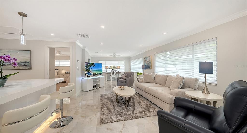 A covered patio features a skylight, a painting, two chairs, a table, and a plant — 1900 BENJAMIN FRANKLIN DRIVE UNIT V11, SARASOTA, FL