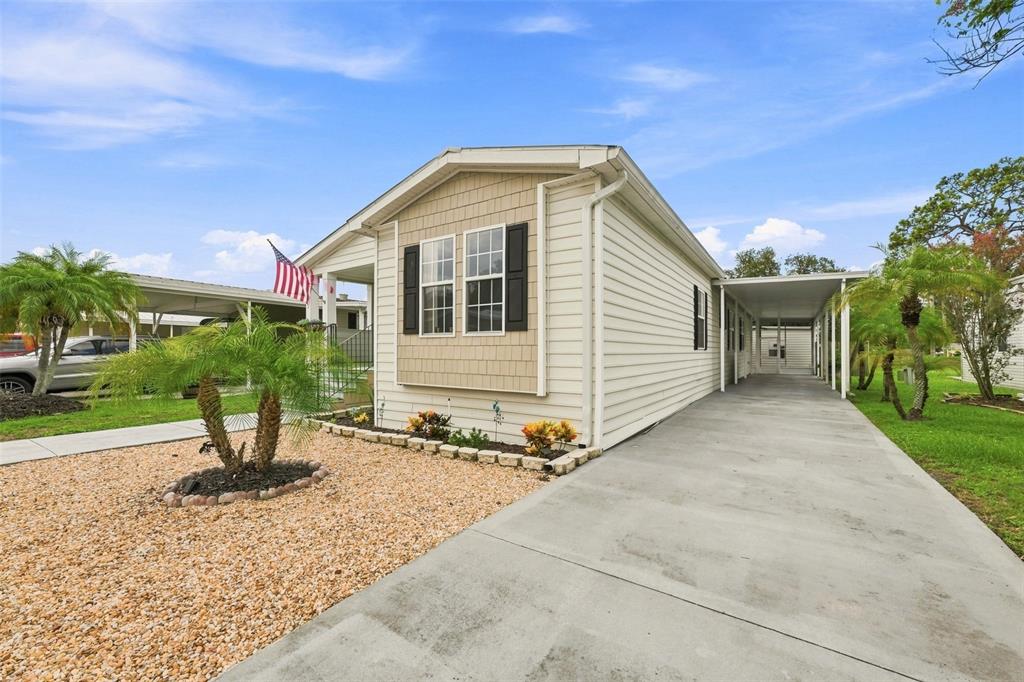 A single-story manufactured home with a concrete driveway, attached carport, and landscaped front yard — 8329 FANTASIA PARK WAY, RIVERVIEW, FL