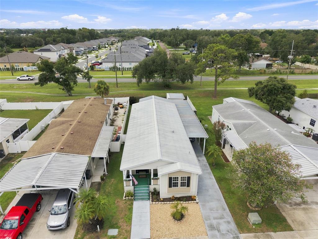 An aerial view shows three single-story houses with metal roofs and carports in a neighborhood — 8329 FANTASIA PARK WAY, RIVERVIEW, FL