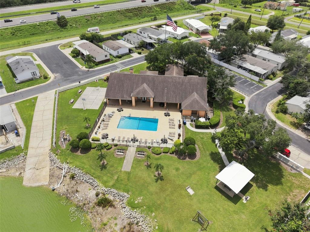 An aerial view shows a community clubhouse with a swimming pool, patio, and adjacent pond — 8329 FANTASIA PARK WAY, RIVERVIEW, FL
