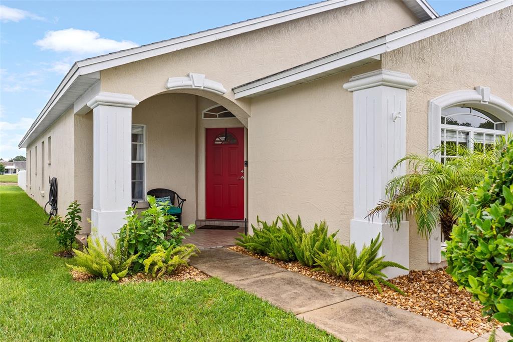 A beige house with a red front door, white columns, and a concrete walkway — 6921 SHIMMERING DRIVE, LAKELAND, FL