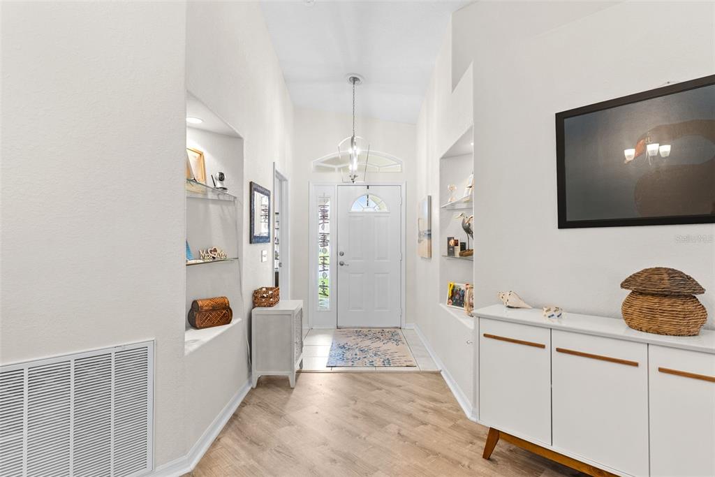 An entryway features light wood flooring, a white front door, and built-in wall niches — 6921 SHIMMERING DRIVE, LAKELAND, FL