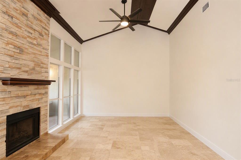 A room with a stone fireplace, tile flooring, vaulted ceiling, and a ceiling fan — 178 W SABAL PALM PLACE UNIT 178, LONGWOOD, FL