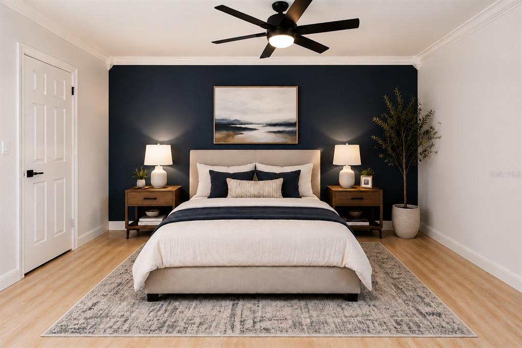 A bedroom features a navy accent wall, a beige upholstered bed, and light wood flooring — 178 W SABAL PALM PLACE UNIT 178, LONGWOOD, FL