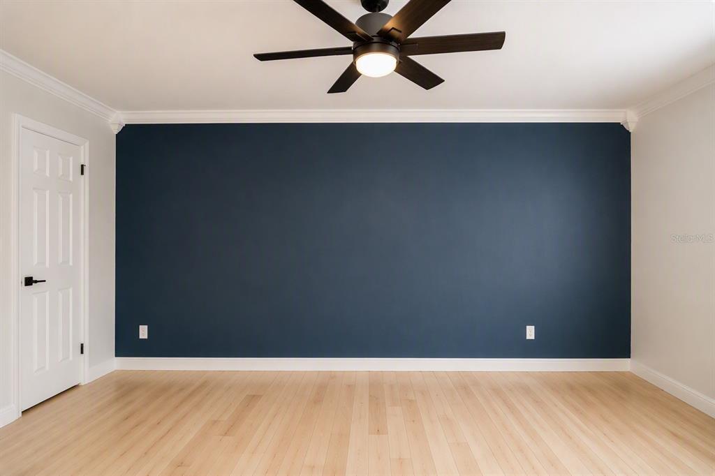 A room with light wood flooring, a dark blue accent wall, and a ceiling fan — 178 W SABAL PALM PLACE UNIT 178, LONGWOOD, FL