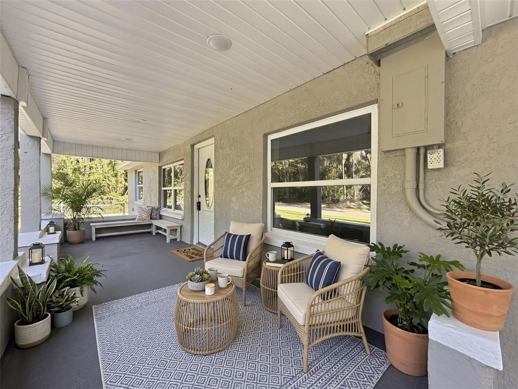 A covered front porch features a seating area with two wicker chairs and a rug — 317 NE 13TH TERRACE, CRYSTAL RIVER, FL