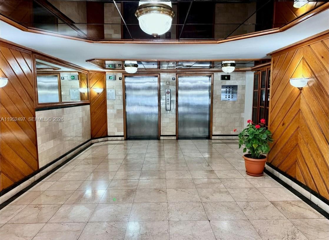 An elevator lobby features wood-paneled walls, a tiled floor, and two stainless steel elevator doors — 2401 Collins Ave # 509, Miami Beach FL 33140, MIAMI BEACH, FL
