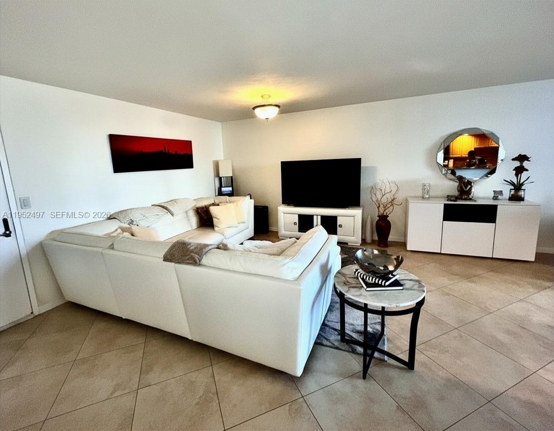A living room features a white sectional sofa, a television on a stand, and tile flooring — 2401 Collins Ave # 509, Miami Beach FL 33140, MIAMI BEACH, FL