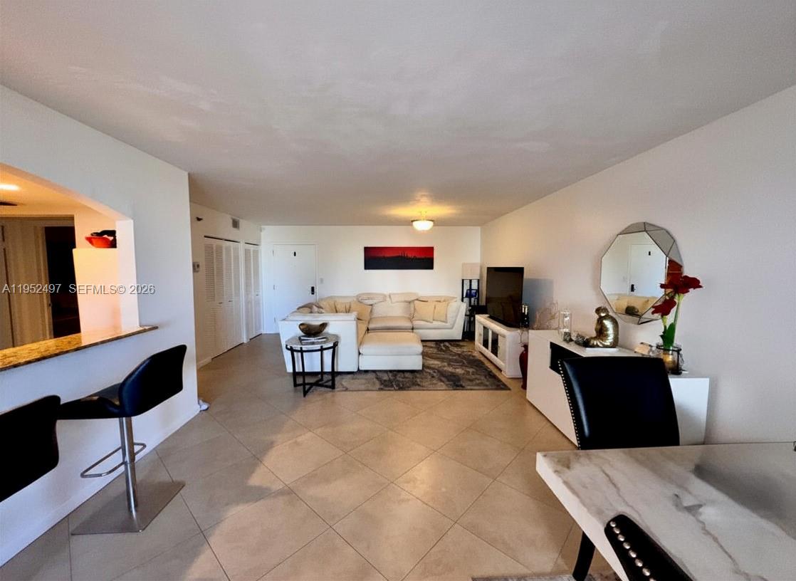 A living room features tile flooring, a white sectional sofa, and a dining area — 2401 Collins Ave # 509, Miami Beach FL 33140, MIAMI BEACH, FL