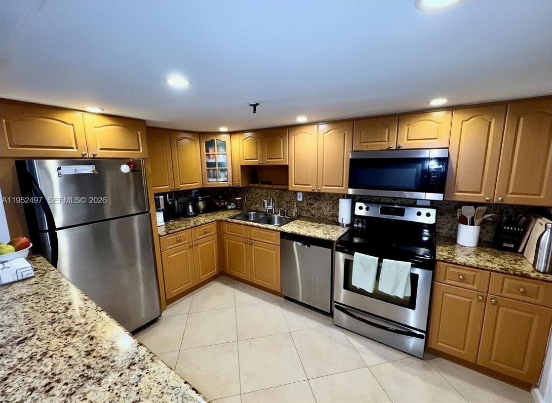 A kitchen features light wood cabinets, granite countertops, and stainless steel appliances — 2401 Collins Ave # 509, Miami Beach FL 33140, MIAMI BEACH, FL