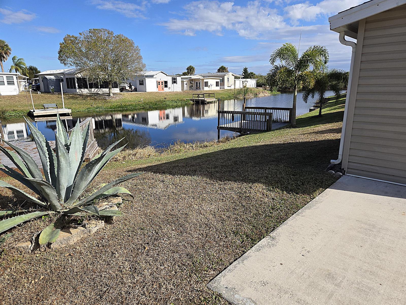 A view of a canal with wooden docks, surrounding houses, and a large agave plant — 14031 SE 126th Terrace, Okeechobee FL 34974, OKEECHOBEE, FL