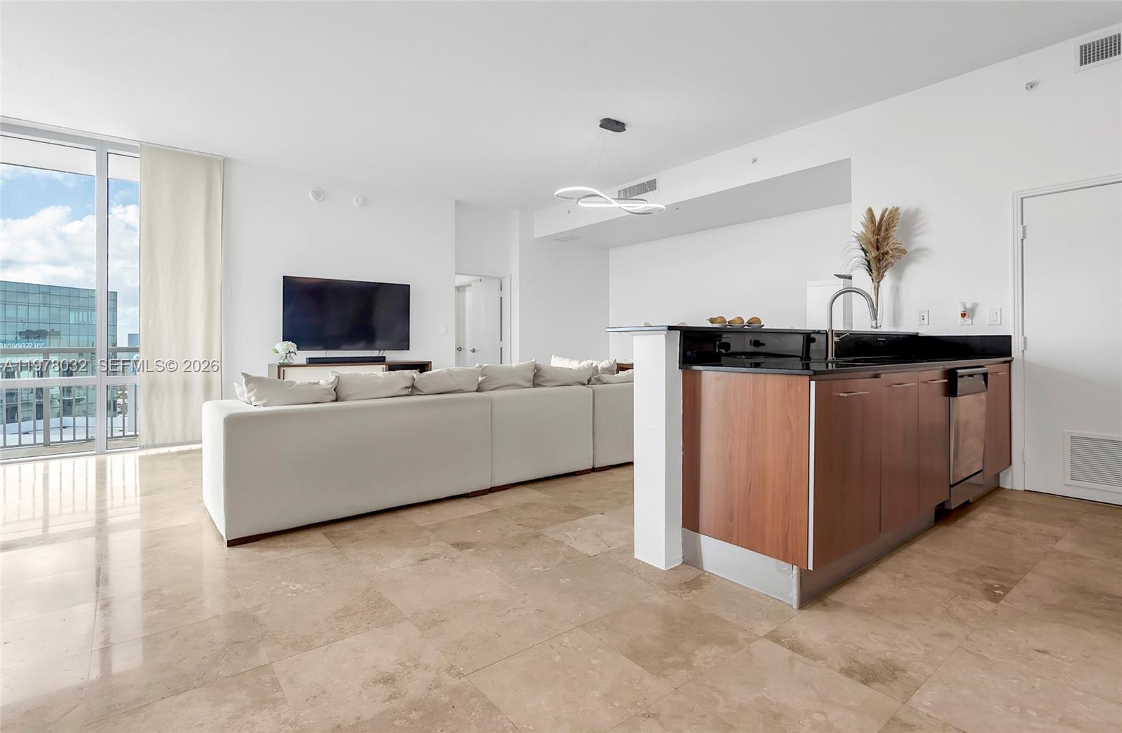 An open-concept living area features a kitchen with dark wood cabinets, stone floors, and a sofa — 9066 SW 73rd Ct, Miami FL 33156, MIAMI, FL